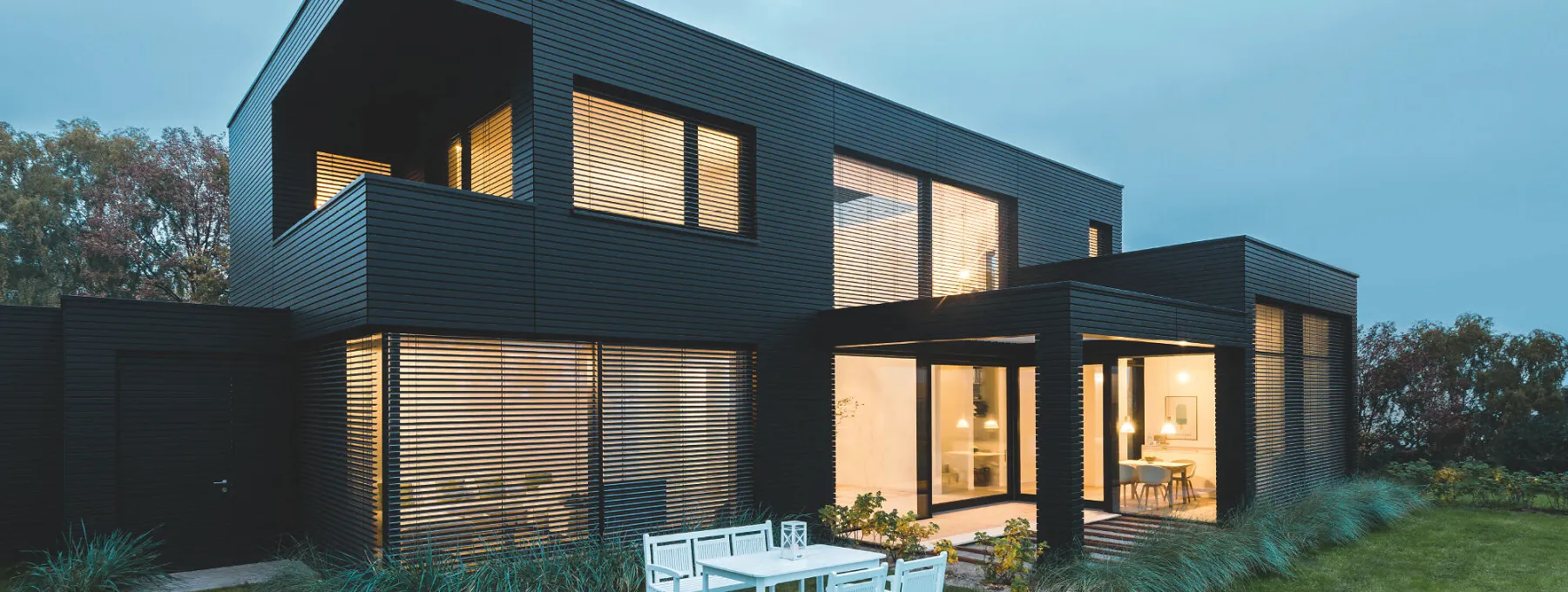 Modern huis in de schemering met binnenverlichting met comfort en design lamellen
