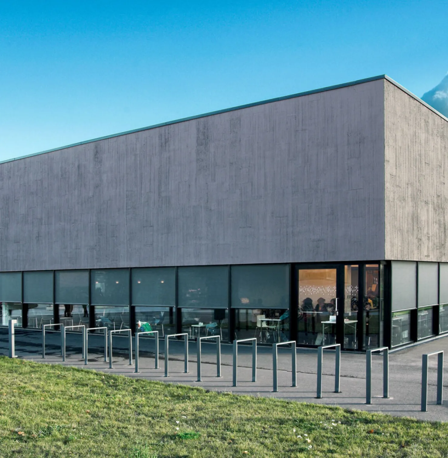 Modern gebouw van twee verdiepingen met ramen rondom en screens van textiel