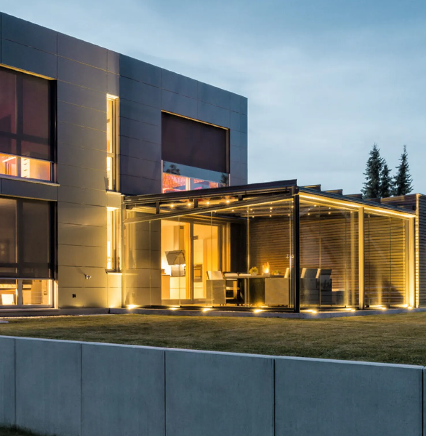 Modern huis in de schemering met binnenverlichting en neergelaten Voorzet screens